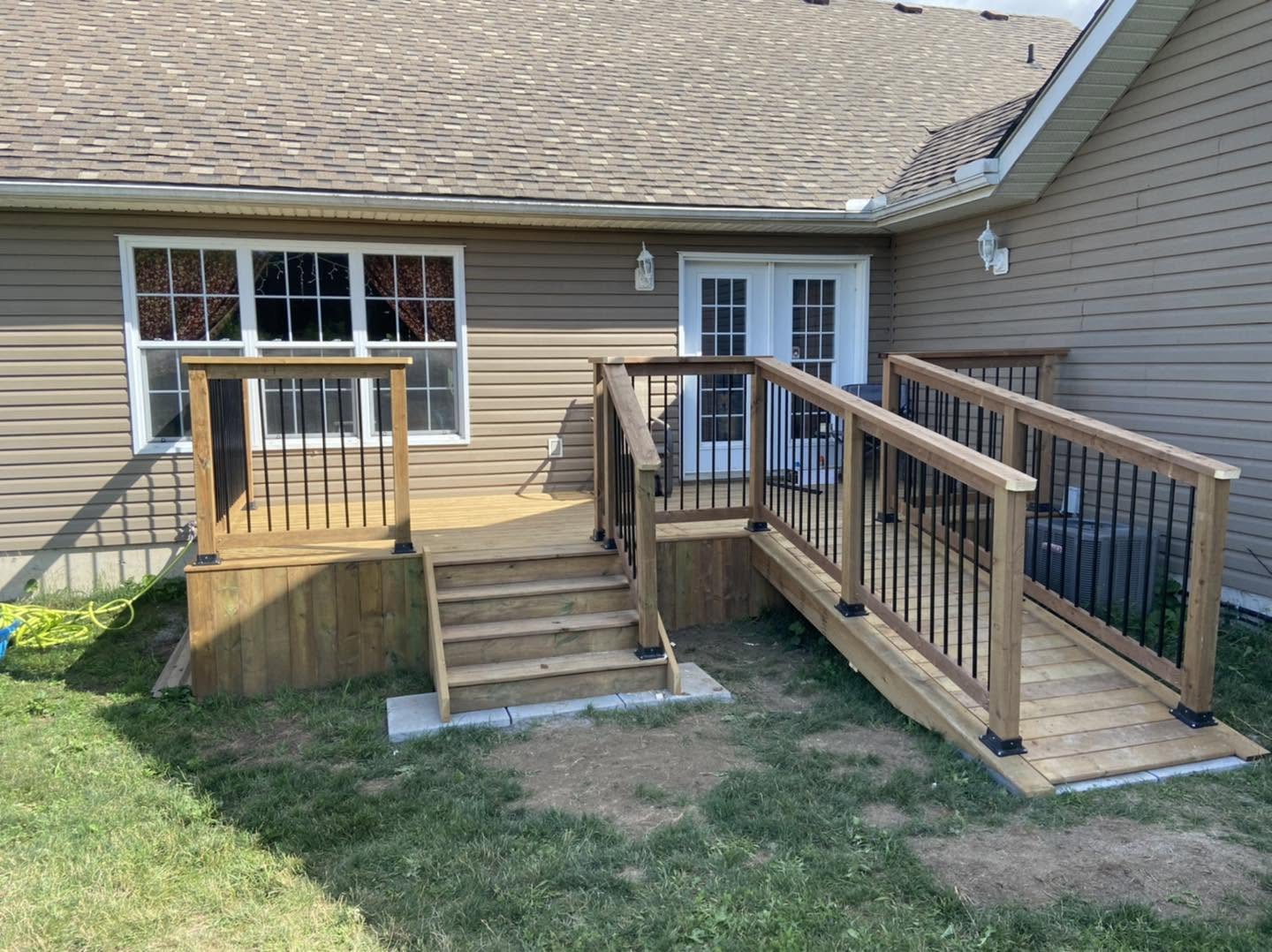 Completed wood deck with stairs, ramp and black railings
